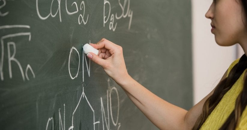 pretty young female college student writing on the chalkboard blackboard during a chemistry class pretty young female college student writing on the chalkboard blackboard during a chemistry class